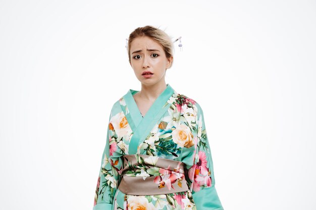 Verärgerte Frau im traditionellen japanischen Kimono, die mit traurigem Ausdruck auf Weiß beiseite schaut