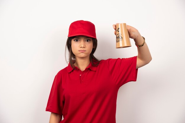 Verärgerte Frau in roter Uniform, die eine leere Tasse hält