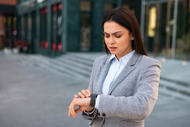 Verärgerte Geschäftsfrau, die ihre Uhr mit Kopienraum betrachtet