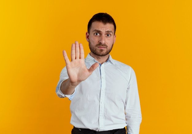 Verärgerte Gesten des gutaussehenden Mannes stoppen Handzeichen lokalisiert auf orange Wand