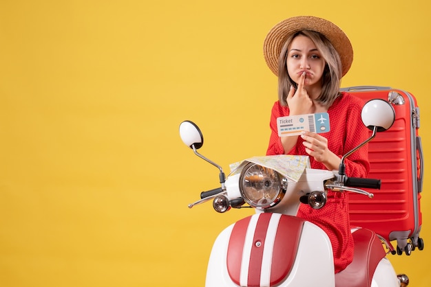 verärgerte junge Dame im roten Kleid mit Ticket auf dem Moped