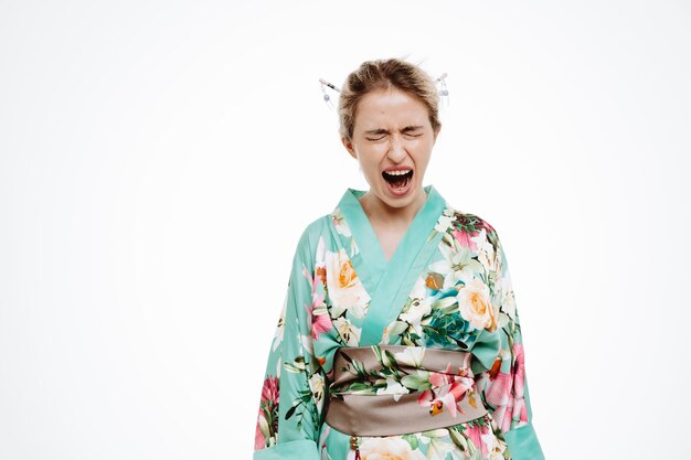 Verärgerte und wütende Frau im traditionellen japanischen Kimono schreit und schreit wild auf Weiß