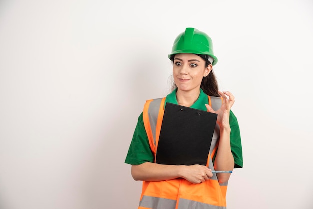 Verärgerter Fraueningenieur mit Klemmbrett auf weißem Hintergrund. Foto in hoher Qualität