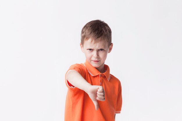 Verärgerter kleiner Junge, der Abneigungsgeste auf weißem Hintergrund zeigt