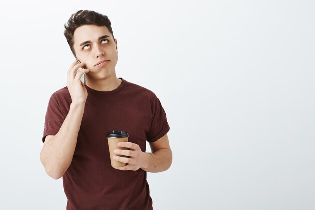 Verärgerter störender gutaussehender Mann mit kurzen dunklen Haaren, der telefonisch spricht