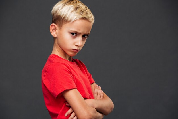 Verärgertes Kind des kleinen Jungen mit den Armen gekreuzt.