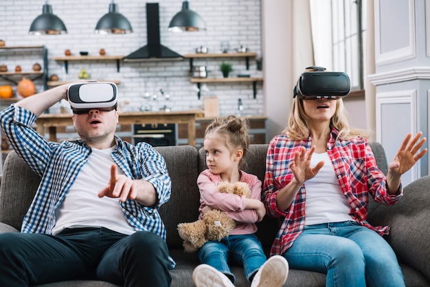 Kostenloses Foto verärgertes mädchen, das ihren vater beim tragen der gläser der virtuellen realität, die auf sofa sitzen, schaut