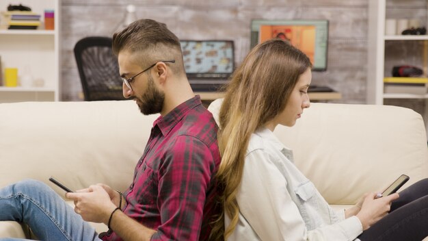 Verärgertes Paar, das Rücken an Rücken sitzt und sich ignoriert. Paar sitzt auf der Couch.