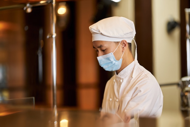 Verantwortliches küchenpersonal mit atemschutzmaske während der arbeit respiratory