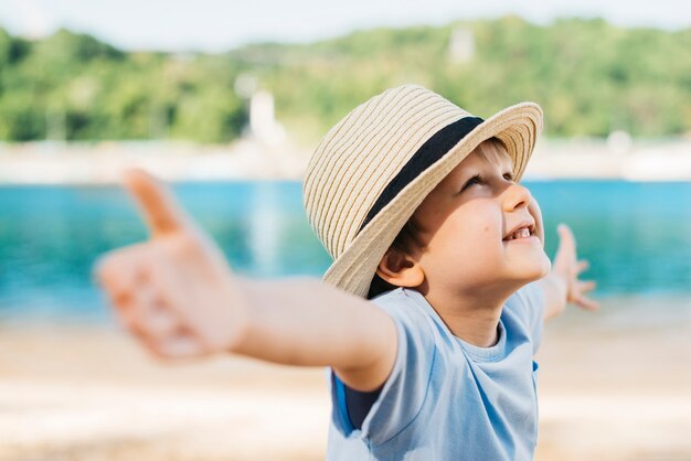 Verbreitende Hände des begeisterten Jungen und oben schauen im Tageslicht