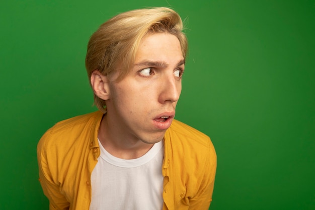 Kostenloses Foto verdächtiger blick auf den jungen blonden mann der seite, der gelbes t-shirt trägt