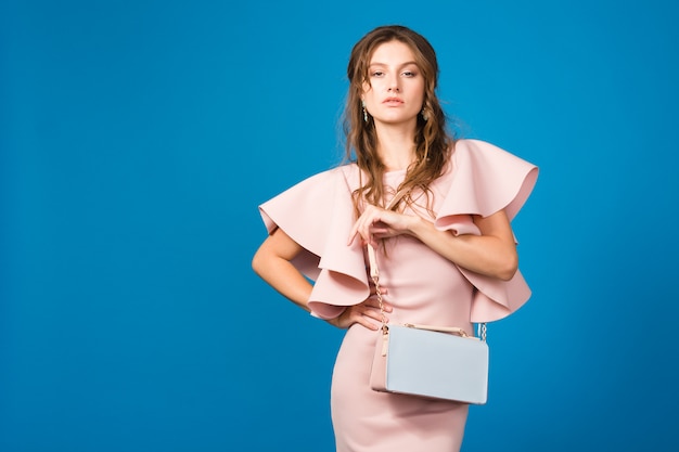 Verführerische junge stilvolle sexy Frau im rosa Luxuskleid, Sommermodetrend, schicker Stil, hält trendige Handtasche