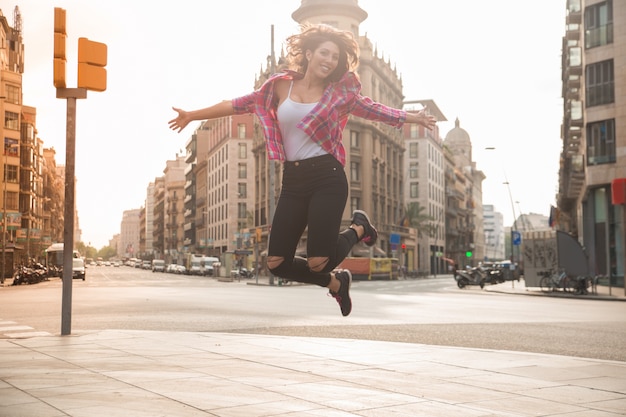 Vergnügte junge Frau springt auf Bürgersteig