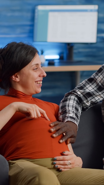 Verheiratetes interracial Paar, das ein Kind erwartet, das zu Hause sitzt