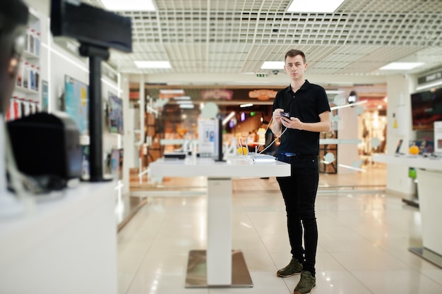 Kostenloses Foto verkäufer mann handy professioneller berater im tech store oder shop halten neues smartphone zur hand