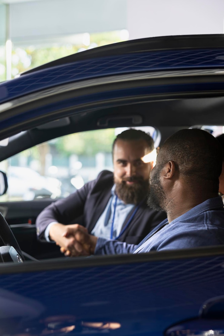 Kostenlose Foto verkäufer schüttelt dem kunden die hand, nachdem er die testfahrt beendet und den deal abgeschlossen hat