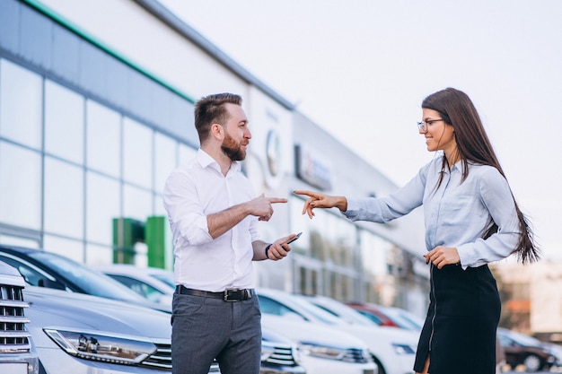 Verkäufer und frau, die nach einem auto in einem autosalon suchen