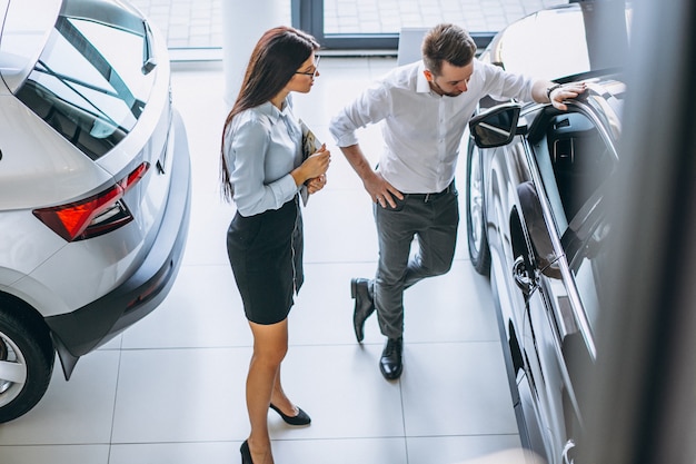 Verkäufer und Frau, die nach einem Auto in einem Autosalon suchen