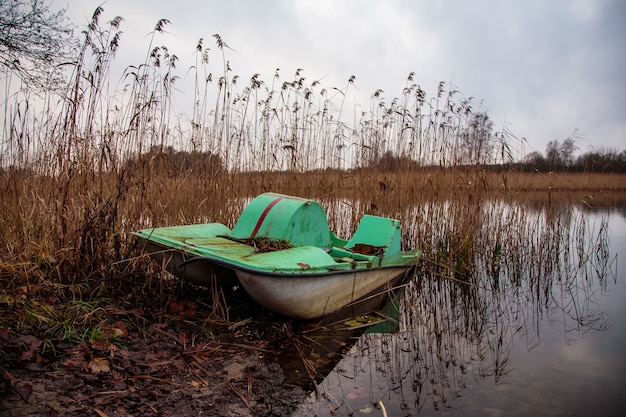 Verlassenes rostiges Paddelboot in der Nähe des Sees in einer schmutzigen Gegend