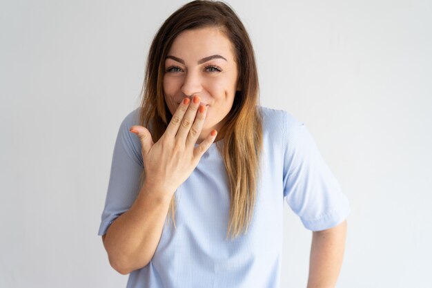 Verlegener hübscher Frauenbedeckungsmund und -lachen