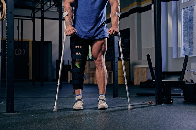 Verletztes Bein des Bodybuilders im Verband mit Krücken.