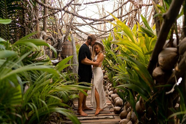 Verliebtes Paar, das Urlaub macht Junges, attraktives, schlankes Mädchen und gutaussehender Mann in Liebe, die sich umarmen und im tropischen Garten spazieren gehen