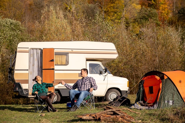 Kostenloses Foto verliebtes paar sitzt auf campingstühlen und genießt das schöne wetter. romantische atmosphäre