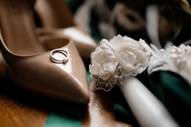 Verlobungsring mit Edelstein liegt auf einem Brautschuh