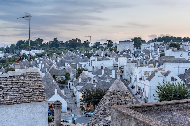 Verlockendes Stadtbild über den traditionellen Dächern der Trulli, originale und alte Häuser dieser Region, Apulien. Typische weiß getünchte Gebäude mit Trockenmauern und konischen Dächern.