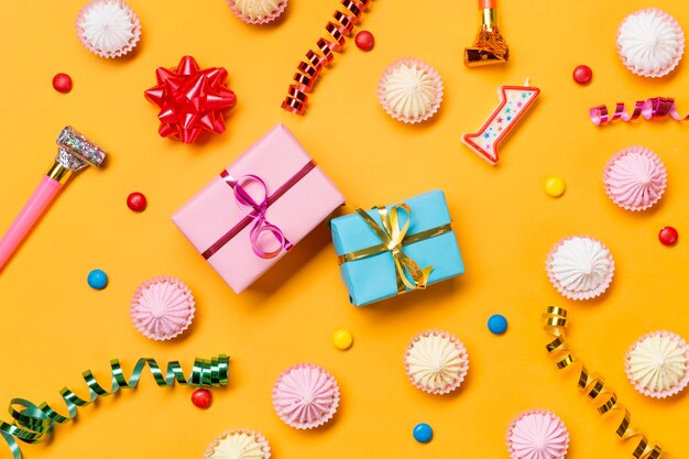 Verpackte Geschenkboxen; aalaw; Luftschlangen; Edelsteine; und verpackte Geschenkboxen vor gelbem Hintergrund