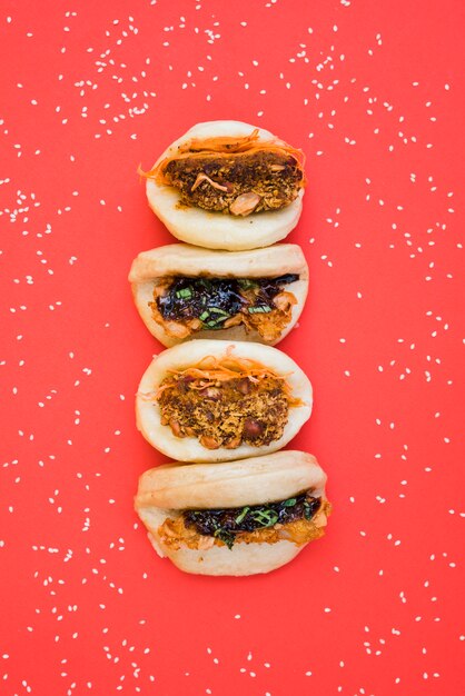 Verschiedene Arten des asiatischen Sandwiches dampften die Gua-bao-Brötchen, die mit Samen des weißen indischen Sesams auf rotem Hintergrund umgeben wurden