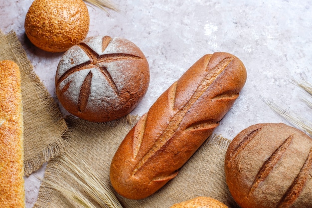 Verschiedene Arten von frischem Brot als Hintergrund, Draufsicht