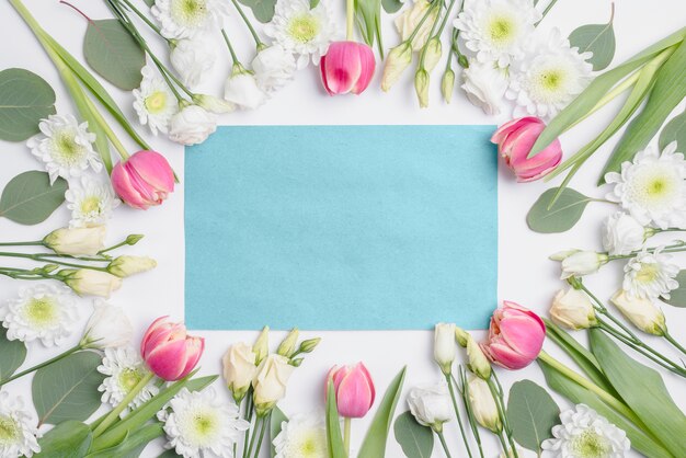 Verschiedene Blumen um blaues Papier
