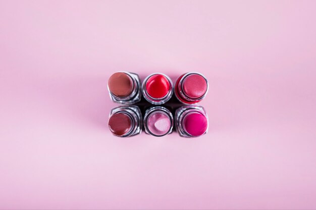 Verschiedene bunte Lippenstifte auf rosa Hintergrund