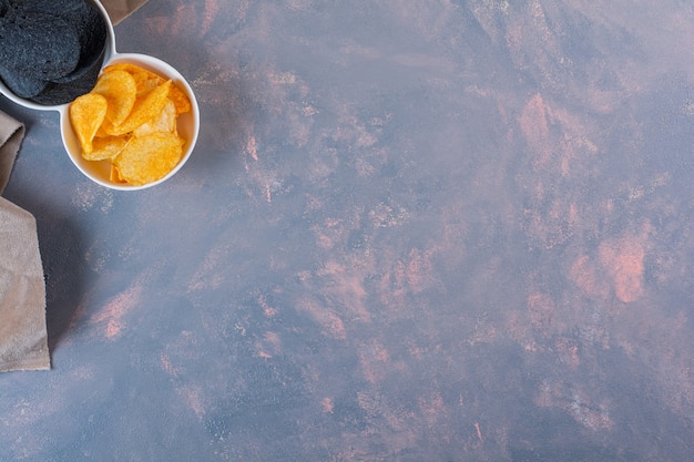 Verschiedene Chips in einer Schüssel auf der Marmoroberfläche