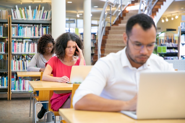 Verschiedene erwachsene Studenten, die an Computer im Klassenzimmer arbeiten