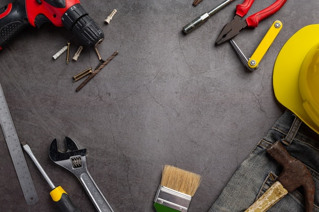 Kostenloses Foto verschiedene handliche werkzeuge auf dunklem hintergrund, hintergrundkonzept des arbeitstages