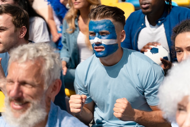 Verschiedene Leute, die eine Fußballmannschaft betrachten