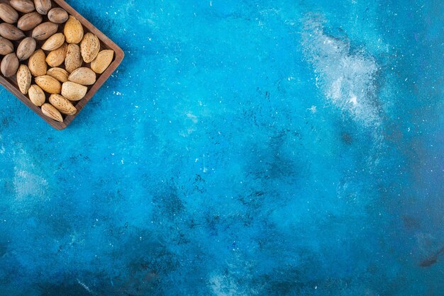Verschiedene Nüsse in einem Brett, auf dem blauen Tisch.