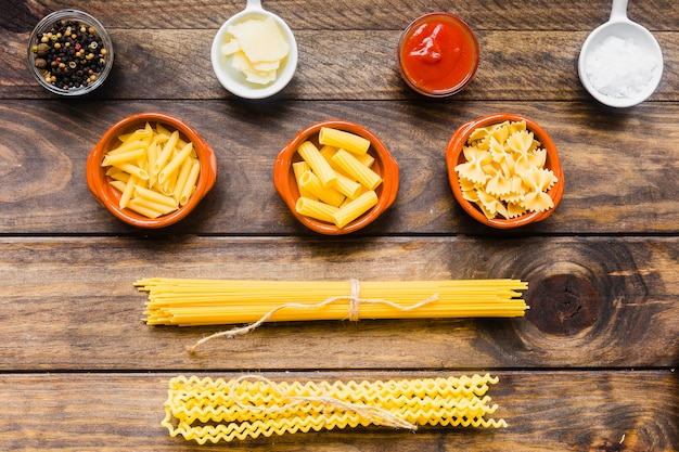 Verschiedene Pasta in der Nähe von Soßen und Gewürzen