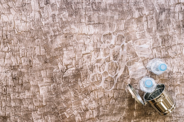 Kostenloses Foto verschiedene plastikmaterialien über mülleimer gegen hölzernen hintergrund