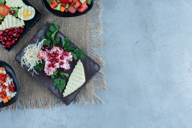 Verschiedene Salate auf Platten auf Marmor.