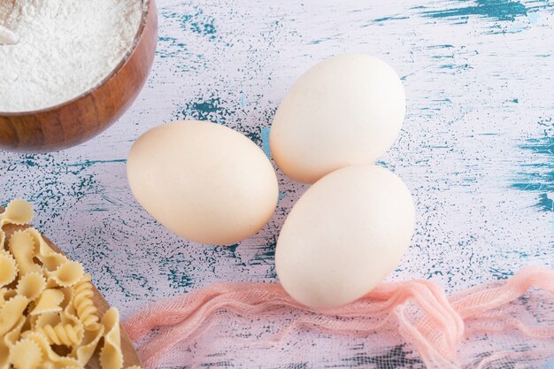 Verschiedene trockene Nudeln mit Mehl und Eiern.