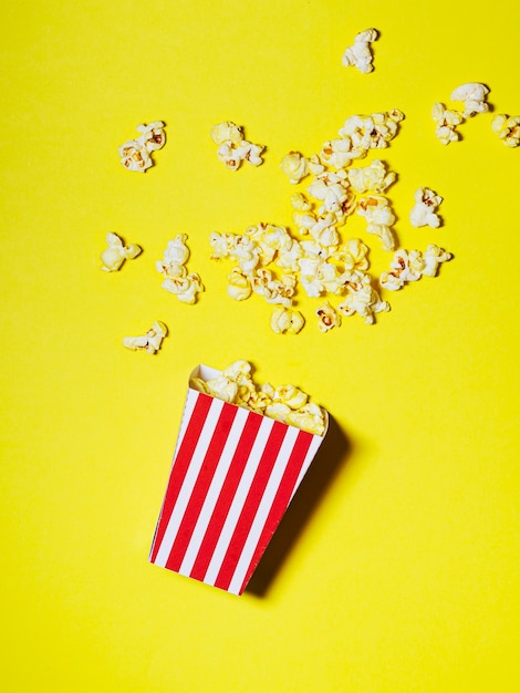 Verschütteter Kasten Popcorn auf gelbem Hintergrund