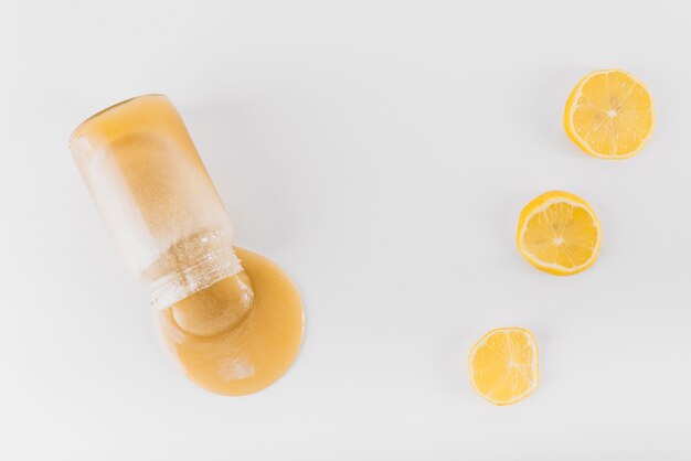Verschütteter Zitronenklumpen von der Flasche auf weißer Oberfläche