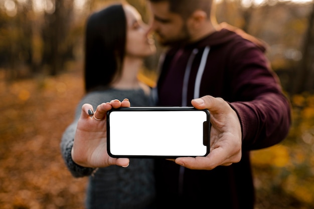 Kostenloses Foto verschwommene partner der nahaufnahme halten smartphone