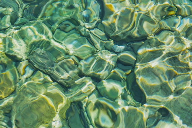 Verschwommener Hintergrund aus transparentem, klarem Wasser in der Meeresbucht des Ägäischen Meeres glitzert in der Sonne, Idee für einen Hintergrund oder eine Postkarte