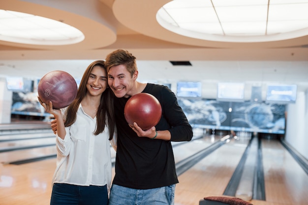 Verspielte Stimmung. Junge fröhliche Freunde haben an ihren Wochenenden Spaß im Bowlingclub