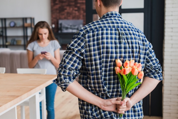 Kostenloses Foto versteckender blumenstrauß des mannes, zum der frau zu überraschen