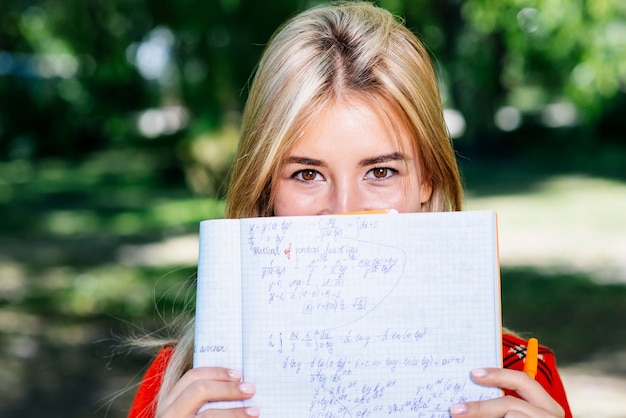 Kostenloses Foto versteckendes gesicht der netten frau mit notizbuch